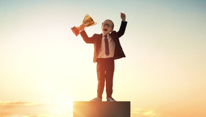 Young boy dressed as business man with trophy
