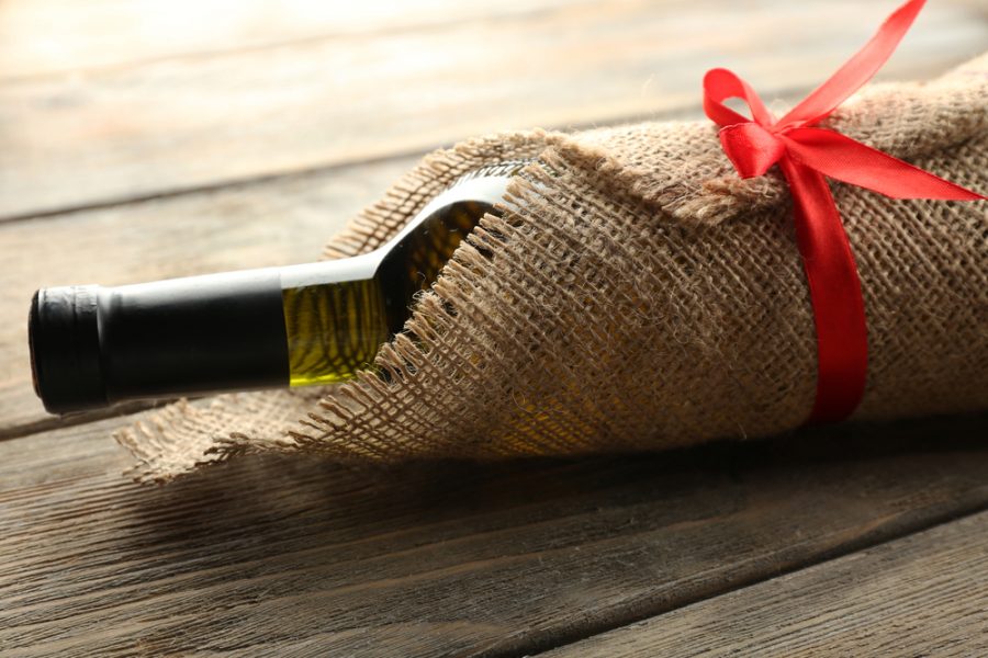 A bottle of wine that is wrapped up ready to be given as a gift by a business owner to a member of staff