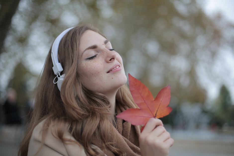 Woman stands with a leaf from a tree and spends some time being mindful