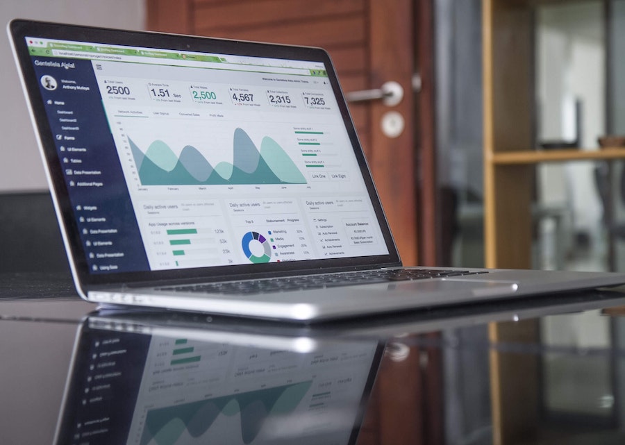 Laptop on a desk with graphs and spreadsheets